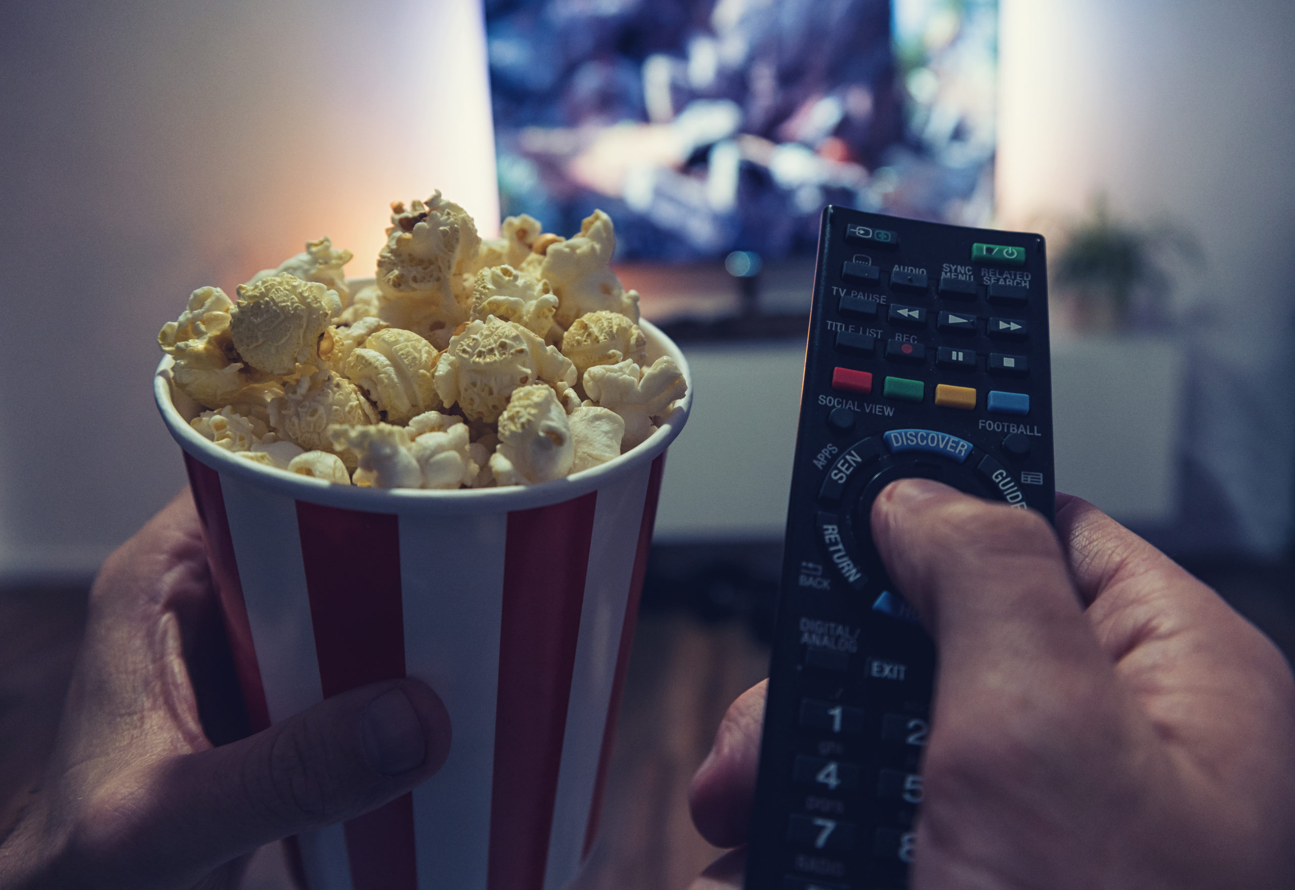 A man watches a movie at home with popcorn